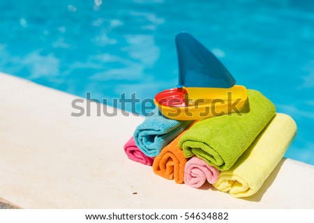 Rolled towels and plastic boat near the swimming pool