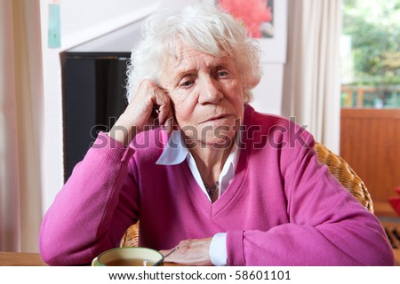 Very old woman in sitting at the table with cup of tea
