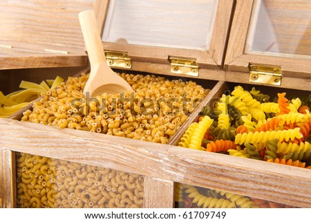 pasta assortment in old wooden cupboard with wooden spoon
