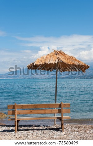 Vertical landscape of Greek beach with empty bench