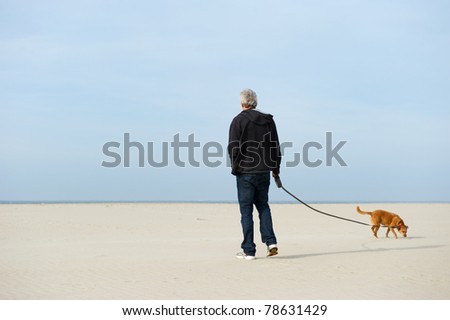 Lonely elderly man with dog at the beach