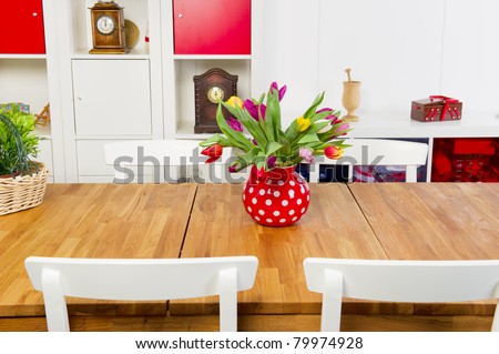 Table and chairs in interior with vase of colorful tulips