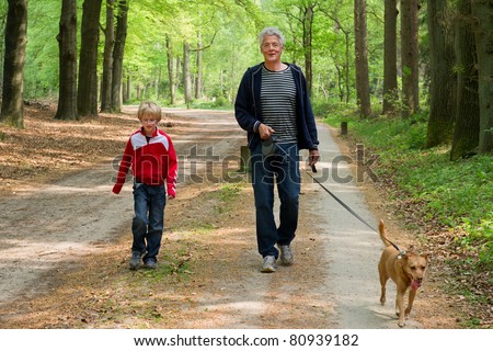 Grandpa and grandchild are walking the dog in the forest