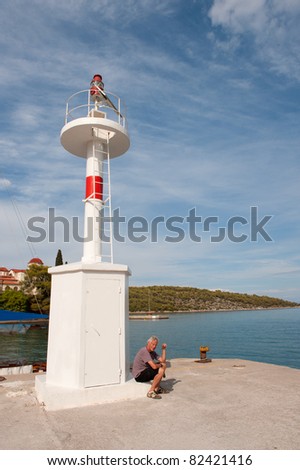 Man sitting near light beacon in Greek harbor Nea Epidavros