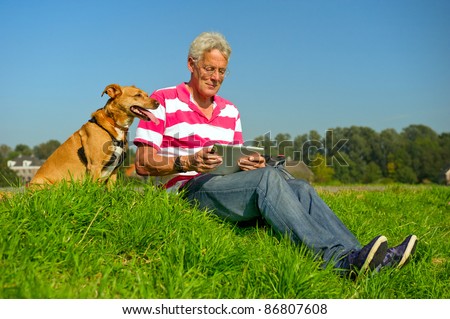 Senior man is reading information at the tablet PC outdoor