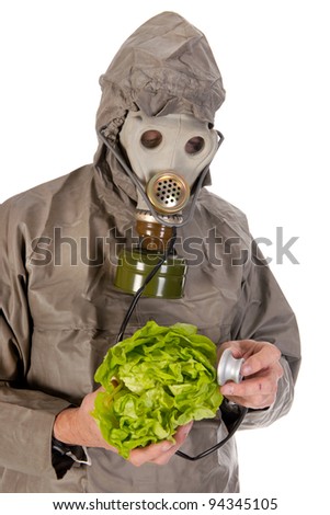 Man dressed in protection suit and gas mask is exploring vegetables