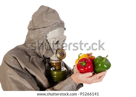 Man dressed in protection suit and gas mask is holding vegetables