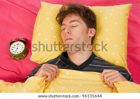Man sleeping in bed with head on yellow pillow