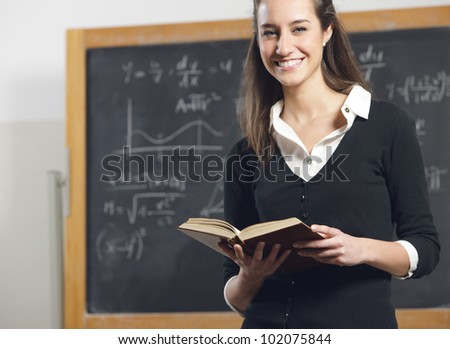 college student or teacher with book in front of a blackboard