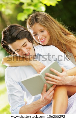 a young couple read a book together in the park. close up.