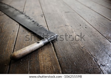 a old saw of a woodcutter is leaning against the old wooden floor. Copy space