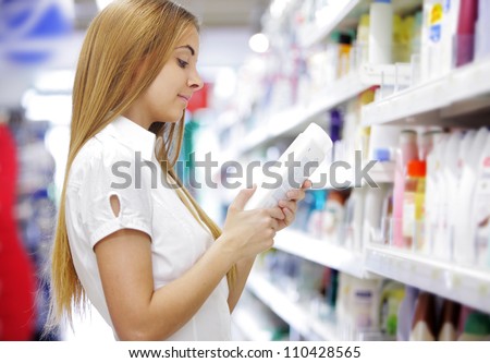woman in a supermarket reading the label behind a package