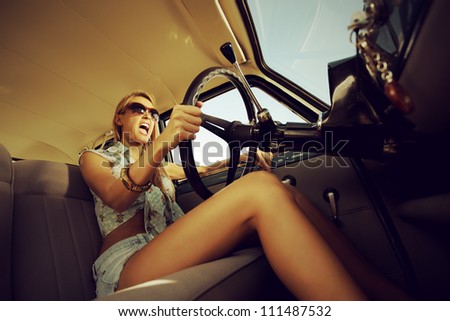 Beautiful young woman driving vintage car.