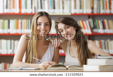 Two female students looking smiling at the library