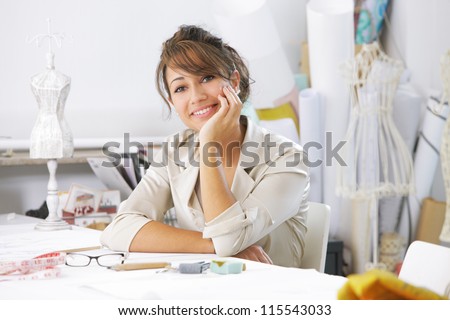 Smiling female fashion designer sitting at office desk