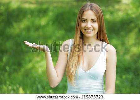 Smiling young woman pointing at copy space on green background