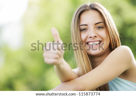 Young Smiling Blond Female Outdoors Showing Thumb Up Sign