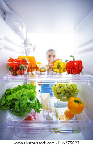 Woman reaching for food in refrigerator, view from inside