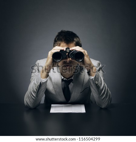 Young businessman looking through binoculars