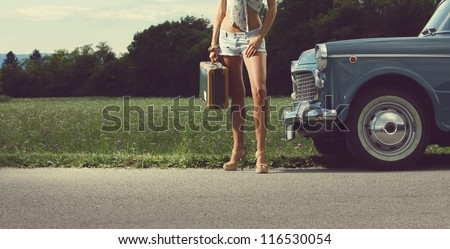 Young sexy girl with suitcase and vintage cars