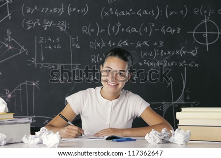 Young student writes in the notebook, in the background a blackboard full of math formulas
