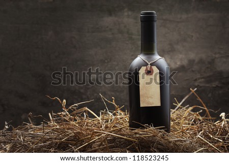 Bottle of red wine in the straw, copy space on vintage label