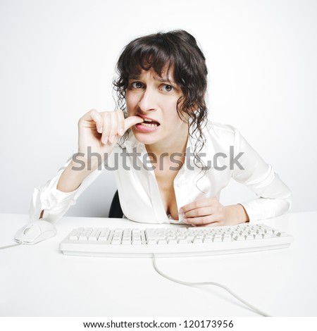 frontal portrait of a doubtful woman nail biting at her office desk
