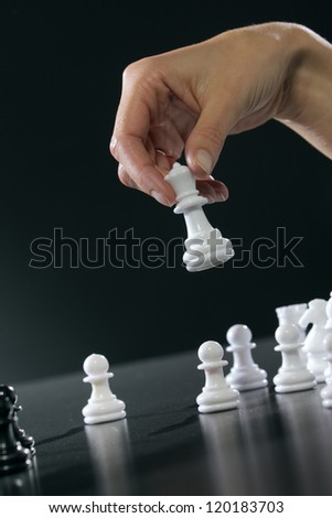 Female hand moving the queen in a chess game.