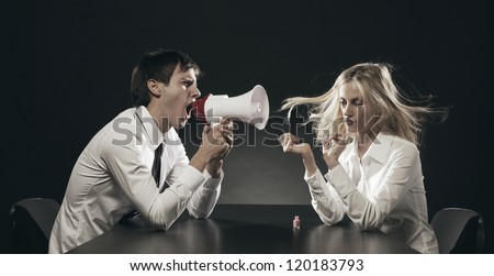 Husband using a megaphone to scream at his wife applying nail polish