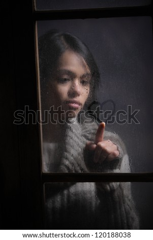 Portrait of woman drawing heart on wet window, focus on rain drop