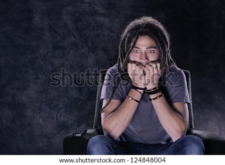 Scared young man watching a scary movie