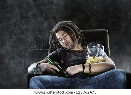 A man sleeps on the couch with beer and chips