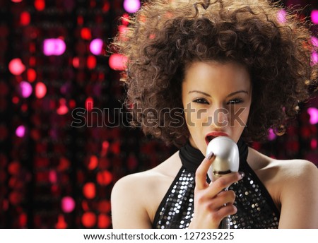 Young female singer with brown curly hair singing a song