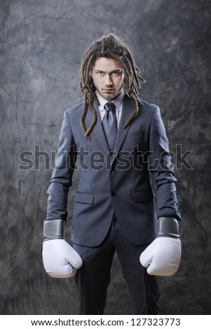 Portrait of a young business man wearing boxing gloves against grunge background