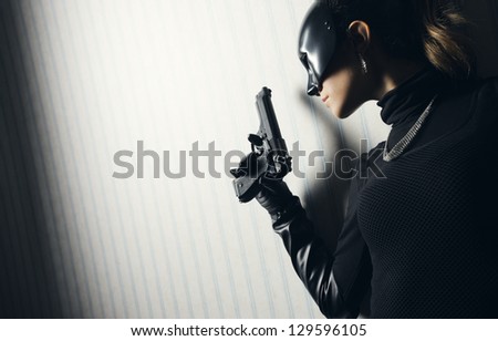 Female thief in black mask with gun