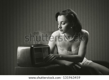 Sensual woman wearing lingerie listening music on old radio