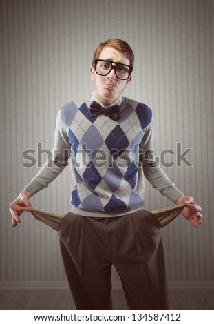 Nerd man stands holding his pockets out showing that he has no money