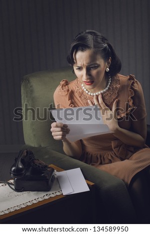 Young woman reading a letter with worried expression