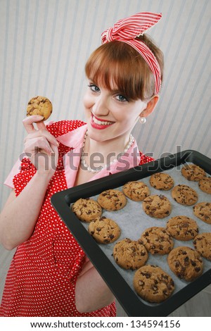 Retro housewife holding cookie tray full of chocolate cookie