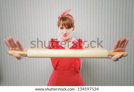 Retro housewife holding a rolling pin, ready to fight