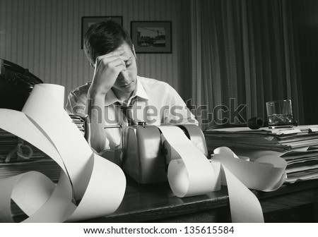Tired businessman is sitting at a table full of paperwork