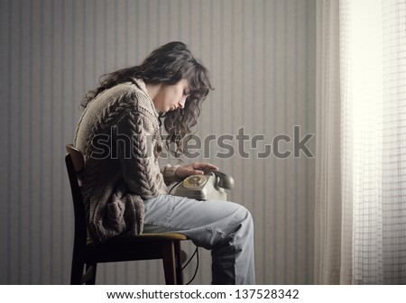 Sad woman sitting on a chair waiting for the phone call