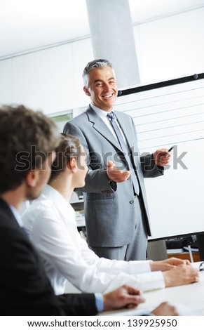 Smiling businessman discussing plans with his colleagues in board meeting