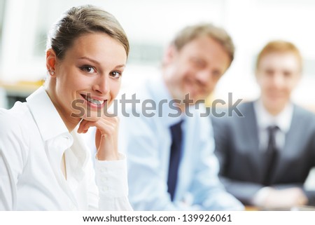 Portrait of a pretty young businesswoman smiling in a meeting with her colleagues in background