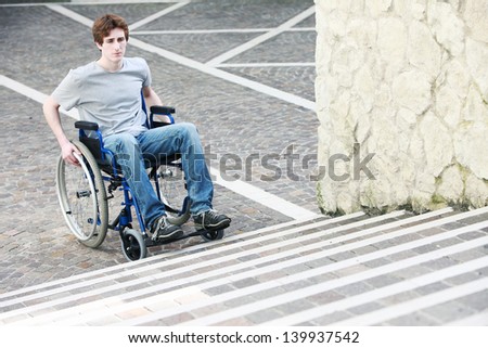 A young man in a wheelchair who can\'t get up the stairs