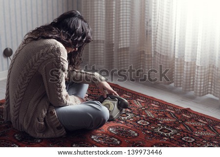 Sad woman sitting on the floor waiting for the phone call
