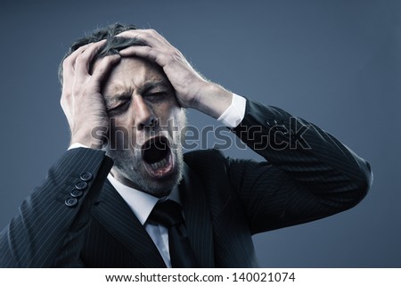 A screaming worried, depressed, and stressed out businessman holds his head