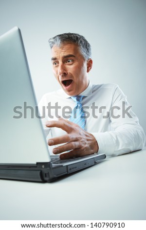 A middle age businessman gets shocked from view of laptop