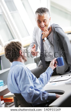 Mature Businessman consulting a partner at desk in office