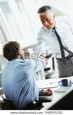Businessmen Shaking Hands In Office